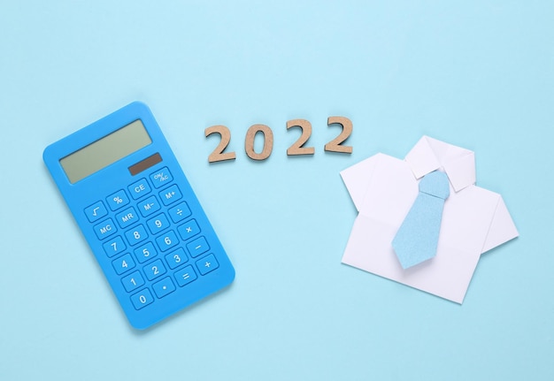 Concept d'entreprise de plan économique Calculatrice chemise origami avec cravate et 2022 sur fond bleu