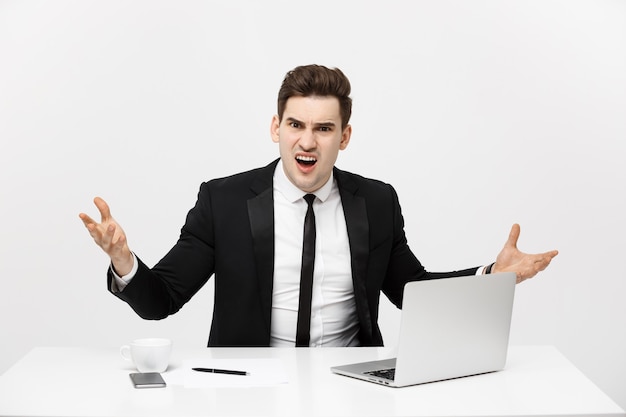 Concept d'entreprise : Portrait d'un homme d'affaires en colère criant assis au bureau isolé sur fond blanc.