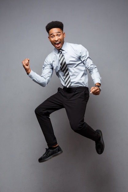 Concept d'entreprise - portrait en pied d'un homme d'affaires afro-américain prospère heureux de sauter au bureau.