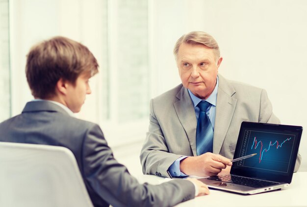 concept d'entreprise, de publicité, de technologie et de bureau - homme plus âgé et jeune homme avec ordinateur portable au bureau