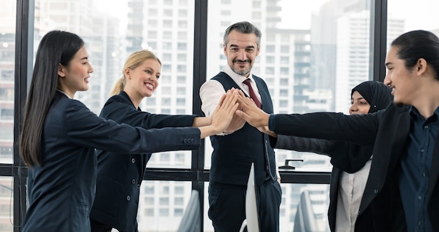 Le concept d'entreprise réussi du travail d'équipe, les dirigeants et le personnel de bureau s'associent pour réussir en tant qu'équipe de petite entreprise dans une salle de réunion avec un sourire heureux et un fond de ville moderne.