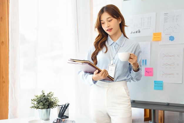 Concept d'entreprise réussi Femme d'affaires debout pour tenir un document et boire du café