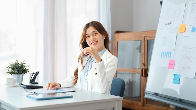 Concept d'entreprise réussi Femme d'affaires tient des lunettes pour sourire à la caméra et assis au bureau
