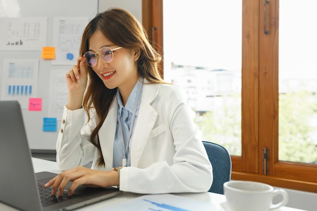 Concept d'entreprise réussi Femme d'affaires utilise la main pour tenir des lunettes tout en tapant des données sur un ordinateur portable