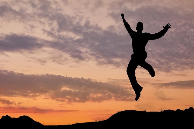 Concept d'entreprise. Silhouette d'un homme sautant au coucher du soleil