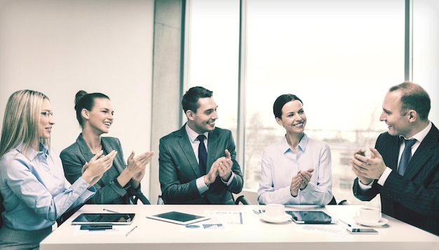 concept d'entreprise, de technologie et de bureau - équipe commerciale heureuse avec des ordinateurs portables, des documents et du café qui applaudit