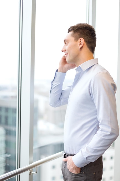 concept d'entreprise, de technologie et de bureau - homme d'affaires souriant avec smartphone au bureau