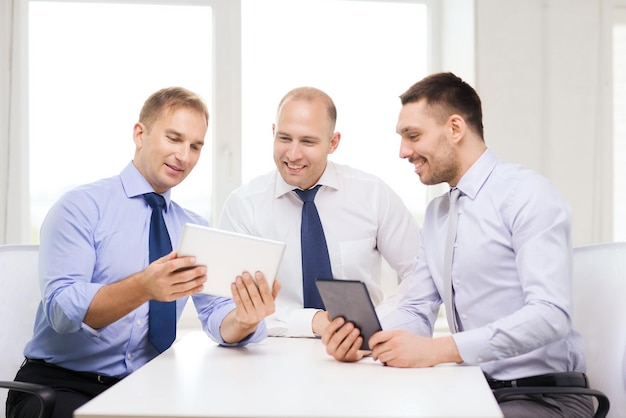 concept d'entreprise, de technologie et de bureau - trois hommes d'affaires souriants avec des ordinateurs tablettes au bureau