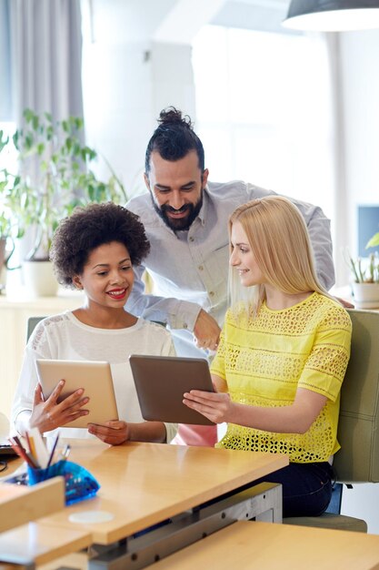 concept d'entreprise, de technologie, de démarrage et de personnes - équipe créative heureuse avec des ordinateurs tablettes au bureau