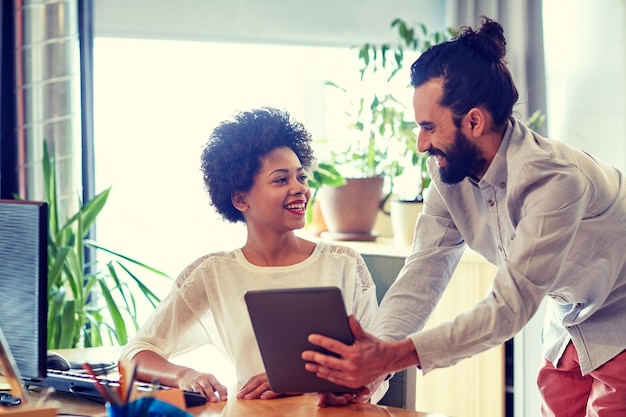 concept d'entreprise, de technologie, de démarrage et de personnes - équipe créative heureuse avec des ordinateurs tablettes au bureau