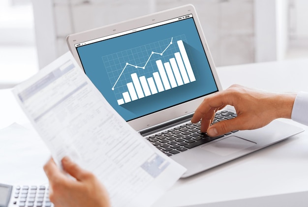 concept d'entreprise, de technologie, de statistiques et de personnes - gros plan d'un homme d'affaires avec graphique sur écran d'ordinateur portable travaillant au bureau