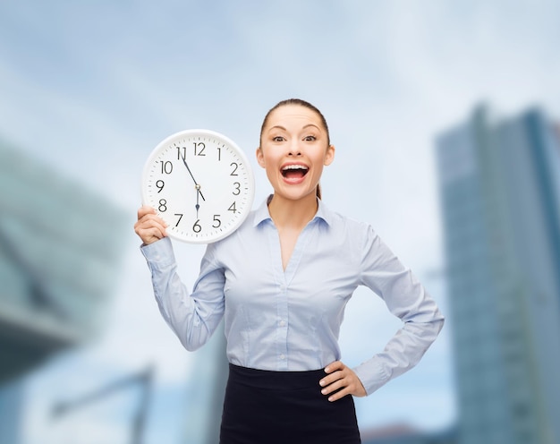 concept d'entreprise et de temps - femme d'affaires attrayante avec horloge murale