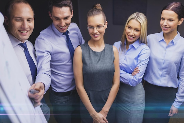 concept d'entreprise, de travail d'équipe et de personnes - équipe commerciale souriante avec tableau à feuilles mobiles discutant au bureau