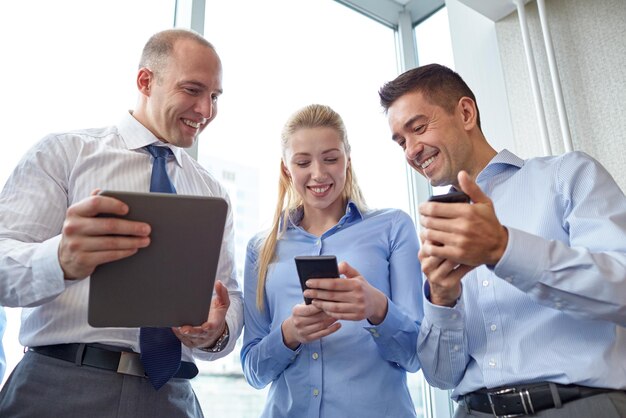 concept d'entreprise, de travail d'équipe, de personnes et de technologie - équipe commerciale avec tablette pc et smartphones se réunissant au bureau