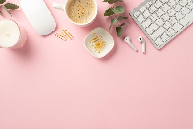 Concept d'entreprise Vue de dessus photo du poste de travail clavier souris d'ordinateur tasse de café écouteurs sans fil clips bougie et eucalyptus sur fond rose isolé avec espace vide