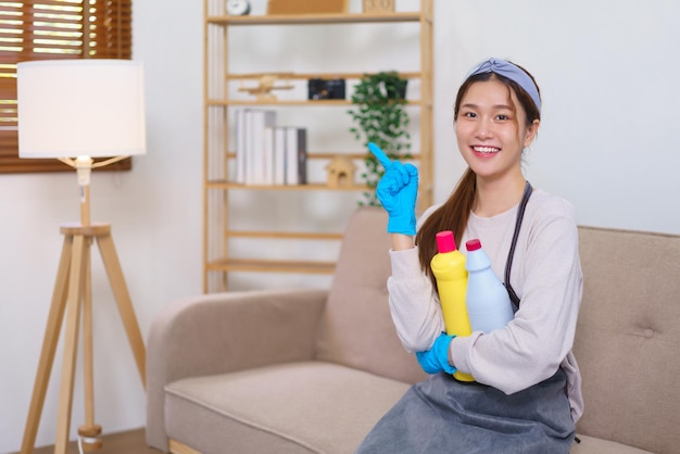 Concept d'entretien ménager Femme de ménage faisant le pouce levé et tenant une solution de nettoyage pour nettoyer la maison
