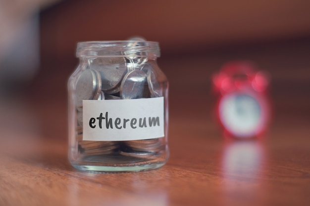 Concept d'épargne pour Ethereum - Pot en verre avec pièces et inscription.