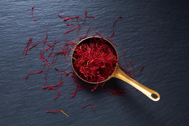 Photo concept d'épices d'ingrédients alimentaires épice de crocus au safran dans une tasse de cuivre sur fond noir avec espace de copie