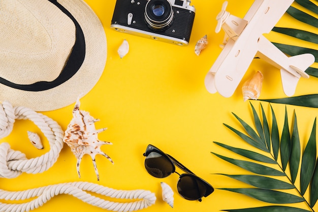 Concept de l&#39;été. Accessoires de voyage: un chapeau de paille, un appareil photo, une corde, un avion en bois, des coquillages, des pantoufles et des lunettes de soleil.