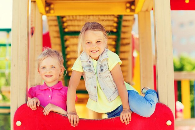 concept d'été, d'enfance, de loisirs, d'amitié et de personnes - enfants heureux sur le cadre d'escalade de l'aire de jeux pour enfants