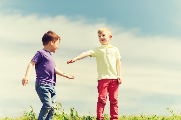 concept d'été, d'enfance, de loisirs et de personnes - petits garçons heureux à l'extérieur sur un champ vert