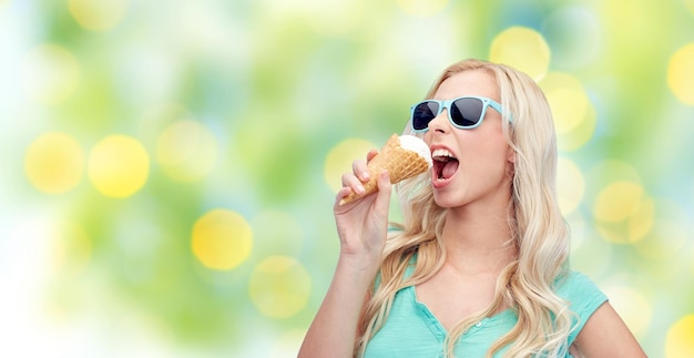 concept d'été, de malbouffe et de personnes - jeune femme ou adolescente en lunettes de soleil mangeant de la glace sur fond de feux verts