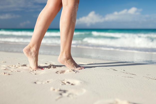 concept d'été, de plage, de loisirs et de partie du corps - gros plan de jambes de femme au bord de la mer