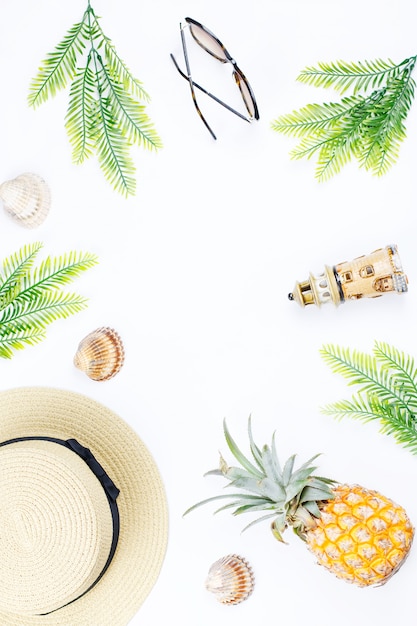 Concept d'été tropical avec des accessoires de mode femme, feuilles et ananas sur fond blanc. Mise à plat, vue de dessus