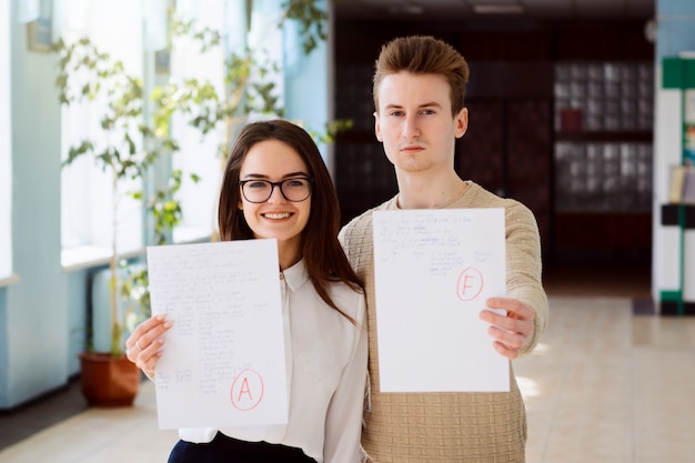 Concept d'examen, test final. Deux étudiants ont reçu le résultat de leur test. Une étudiante a obtenu d'excellentes notes alors qu'un étudiant a obtenu une mauvaise note.