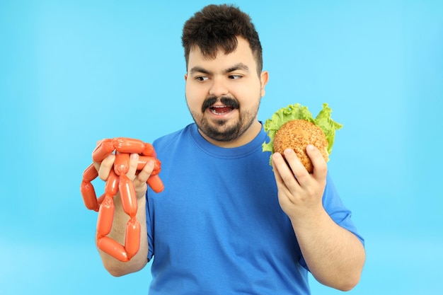 Concept d'excès de poids gros gars avec de la nourriture sur fond bleu