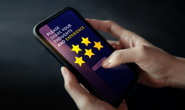 Concept d'expériences client. Femme utilisant un téléphone portable pour donner des commentaires via Internet. Avis positif avec cinq étoiles. Enquêtes de satisfaction client