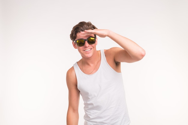 Concept d'expression et de geste - Bel homme drôle dans des lunettes de soleil sur une surface blanche