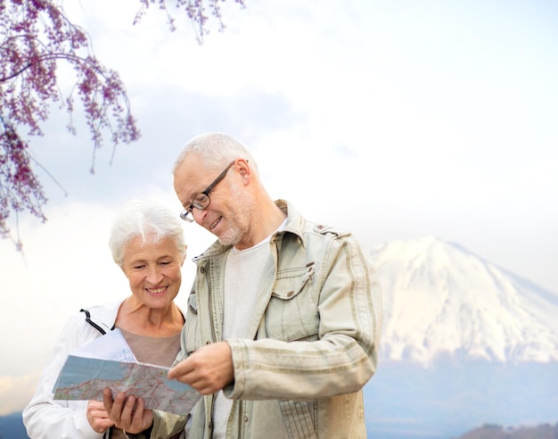 concept de famille, d'âge, de tourisme, de voyage et de personnes - couple de personnes âgées avec carte et guide de la ville sur fond de montagnes du japon