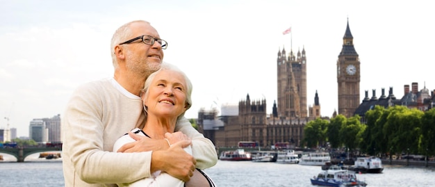 concept de famille, d'âge, de tourisme, de voyage et de personnes - couple de personnes âgées heureux sur les chambres du parlement ou le palais de westminster et la tour de l'horloge big ben à londres