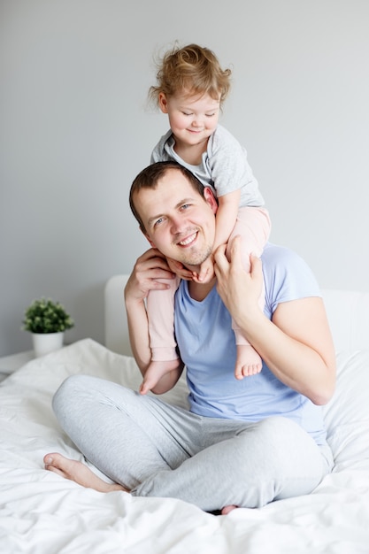 Concept de famille, d'amour, de bonheur et de paternité - père heureux s'amusant avec sa petite fille mignonne