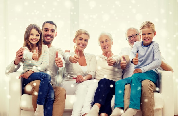 concept de famille, de bonheur, de génération et de personnes - famille heureuse assise sur un canapé et montrant le geste du pouce levé à la maison