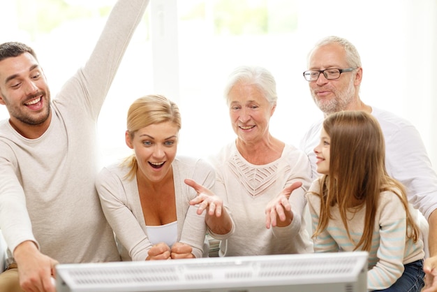 concept de famille, de bonheur, de génération et de personnes - famille heureuse assise sur un canapé et regardant la télévision à la maison