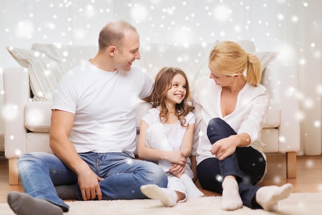 concept de famille, d'enfance, de communication, de personnes et de maison - parents souriants avec une petite fille assise sur le sol à la maison