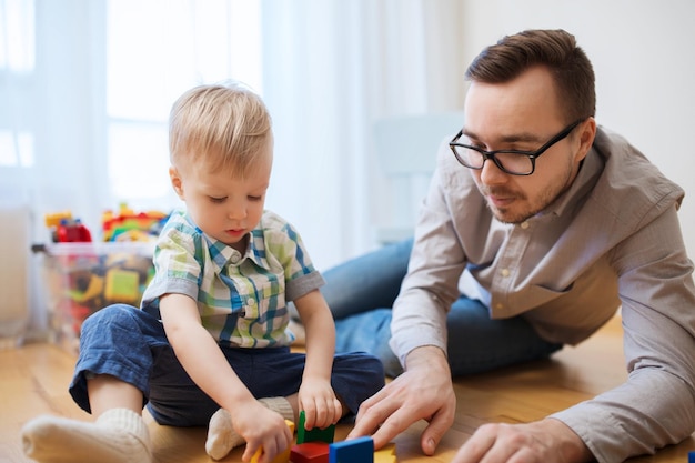 concept de famille, d'enfance, de créativité, d'activité et de personnes - père heureux et petit fils jouant avec des blocs de jouets à la maison