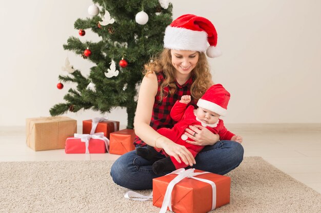 Concept de famille, d'enfance et de Noël - Portrait d'une mère heureuse et d'un adorable bébé en costume de Père Noël.