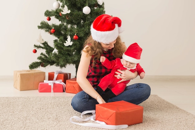 Concept de famille, d'enfance et de Noël - Portrait d'une mère heureuse et d'un adorable bébé en costume de Père Noël.