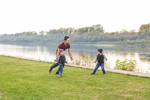 Concept de famille d'enfance père jouant avec deux fils près du lac
