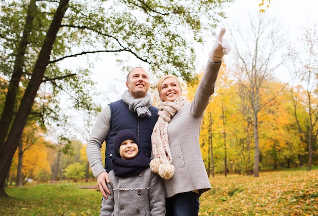 concept de famille, d'enfance, de saison, de geste et de personnes - famille heureuse pointant du doigt dans le parc d'automne