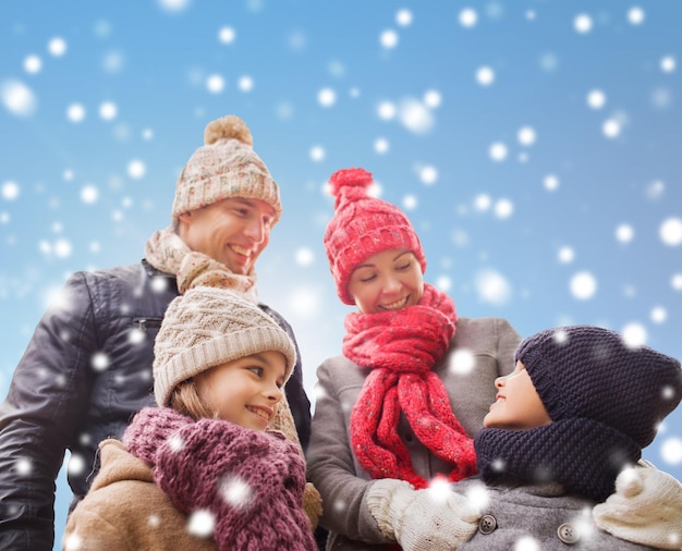 concept de famille, d'enfance, de saison et de personnes - famille heureuse en vêtements d'hiver sur fond bleu neigeux