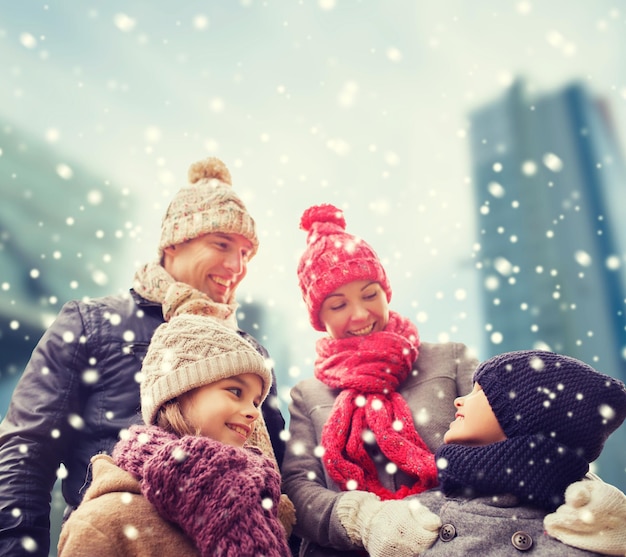 concept de famille, d'enfance, de saison et de personnes - famille heureuse en vêtements d'hiver sur fond de ville enneigée