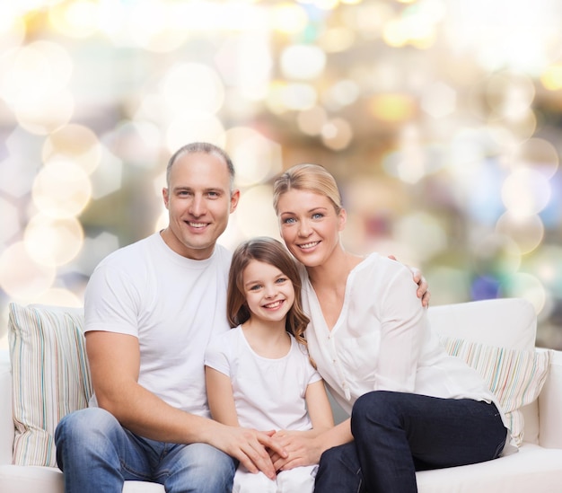 concept de famille, d'enfance, de vacances et de personnes - mère souriante, père et petite fille sur fond de lumières