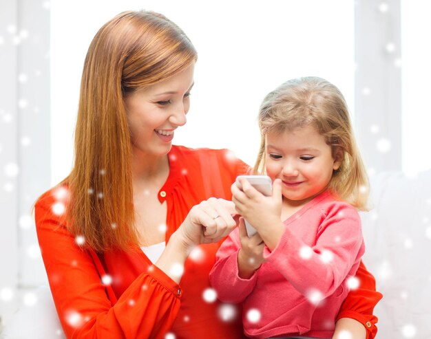 concept de famille, d'enfance, de vacances, de technologie et de personnes - heureuse mère et fille avec smartphone à la maison