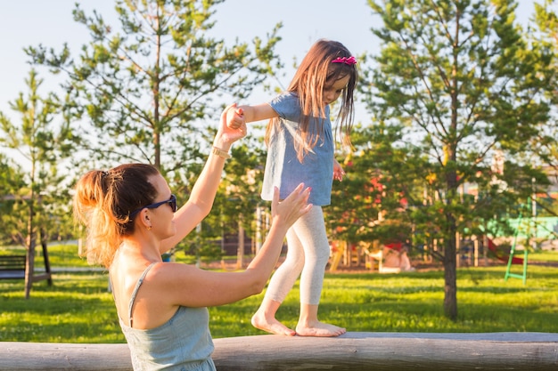 Concept de famille et d'enfant mère et fille marchant et jouant dans le parc et profitant de la