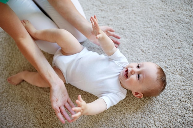 Concept de famille, enfant et parentalité - heureuse jeune mère souriante jouant avec petit bébé à la maison