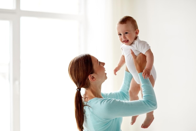 Concept de famille, d'enfant et de parentalité - jeune mère souriante heureuse avec petit bébé à la maison